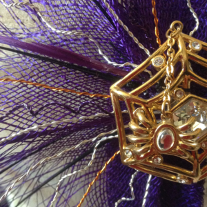 A spider themed head piece in purple and gold.